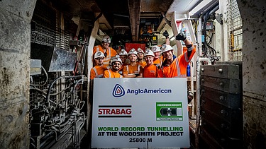 Foto von mehreren Personen, die einen Tunneldurchstich feiern und eine große Tafel in der Hand halten