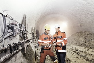 Foto von zwei Tunnelbauarbeitern bei einer Maschine