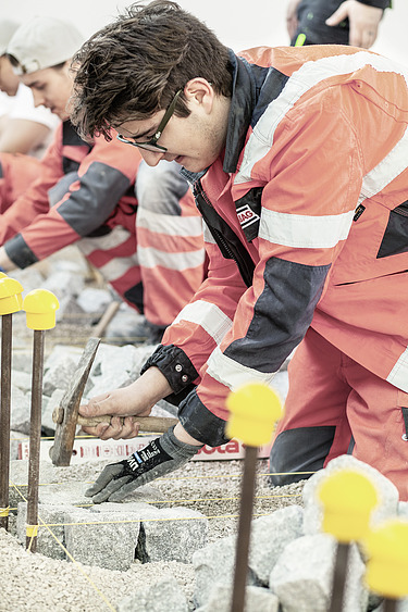 Das Bild zeigt zwei Personen in Arbeitskleidung bei der Arbeit