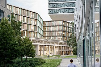 Das Bild zeigt ein Bürogebäude, im Vordergrund eine Person mit einem Fahrrad